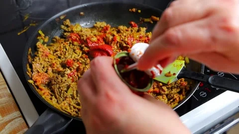 Woman adding tomato paste to minced meat. Bolognese sauce is prepared in a Stock Footage 277587600