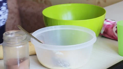 The woman adds an egg to the container. For making dough. Cooking gingerbread Stock Footage 196983377