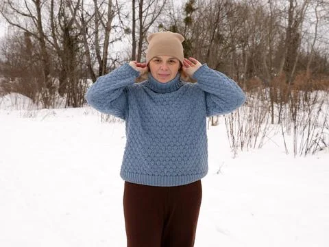 Woman adjusting a winter hat while walking through a snowy landscape, enjoyin Фото