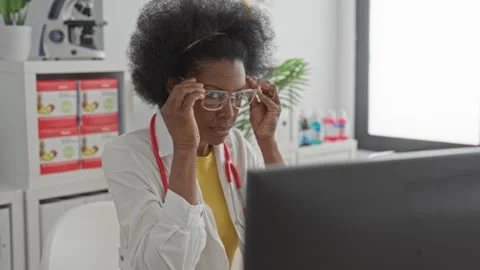 Woman adjusts glasses while touching white coat and stethoscope in medical .. Stock Footage 337377975