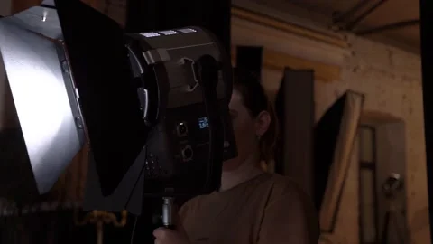 A woman adjusts a light device on the set. Professional content creation Stock Footage 148109301