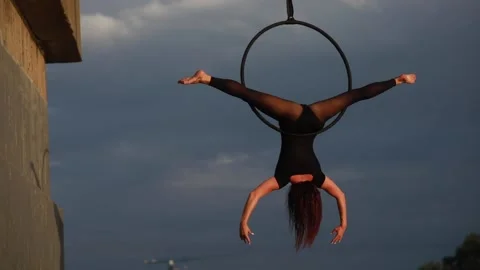 Woman aerialist performs acrobatic elements and spins in hanging aerial hoop. 動画素材 137030715