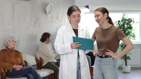 Woman after the interview communicates with nurse to get a medical book for Video stock 341783547