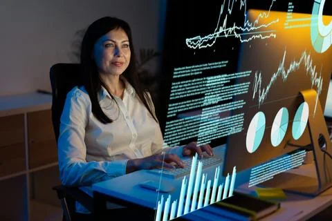 Woman Analyzing Data on Virtual Screen at Night in Modern Office Foto stock