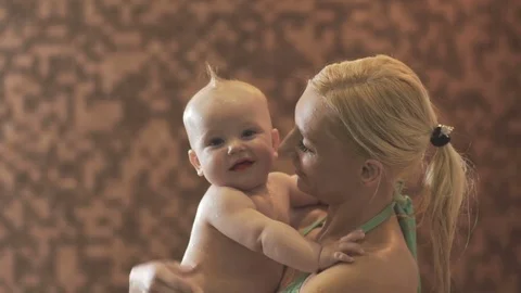 Woman and child after water procedures. Woman kisses happy baby Stock Footage
