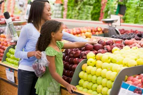 Woman and daughter shopping for apples at a grocery store Stock Photos