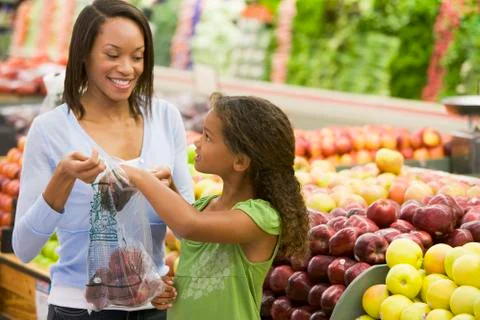 Woman and daughter shopping for apples at a grocery store Stock Photos