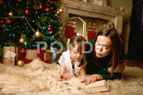 Woman and he daughter lying on the floor and reading book Stock Photos