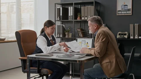 Woman and Man Exchanging Documents, Discussing Bank Mobile App Stock Footage 330961442