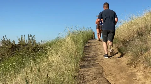 Woman and man jogging up trail in Boise, Idaho with Boise skyline Vídeos de archivo 132343553