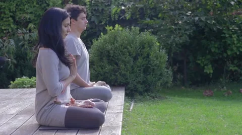A woman and man meditating on terrace Stock Footage