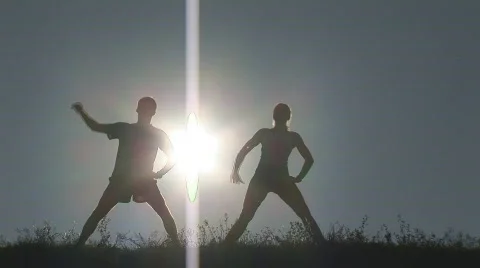 Woman and man stretching infront of sunset Stock Footage