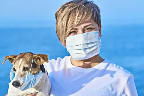 Woman and pet wearing face mask as virus protection concept Stock Photos