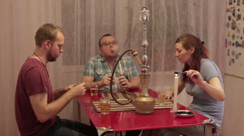 A woman and two men smoking shisha and talking Stock Footage 59571798