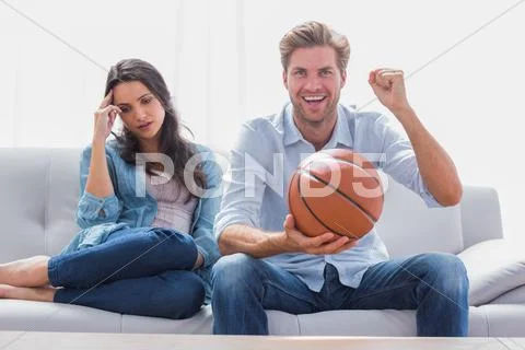 Woman annoyed by her partner watching basketball game Stock Photos