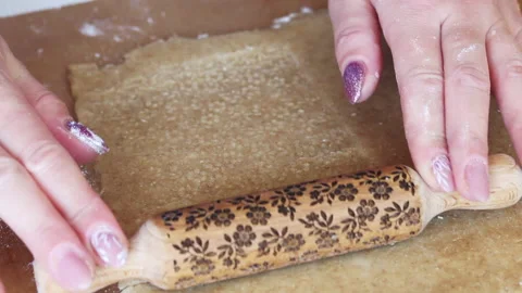 A woman applies a pattern to the rolled out dough. Using a wooden rolling pin Stock Footage 196982453