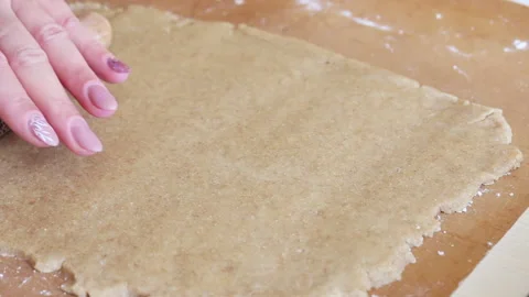 A woman applies a pattern to the rolled out dough. Using a wooden rolling pin Stock Footage 196982533