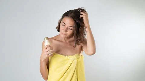 A woman applies serum balm to hair after a shower Stock Photos