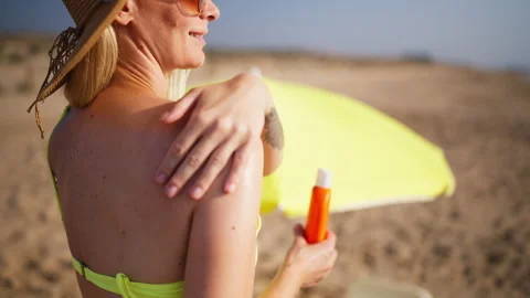 Woman apply sunscreen to shoulder while relax on  beach. Daily SPF skincare.. 库存影片 340903486
