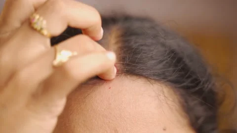 Woman applying bindi to forehead Vidéo 137216785