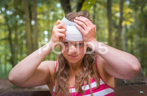 Woman Applying Compression Bandage On Her Head After Injury In Nature