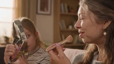Woman Applying Cosmetics while Teaching Daughter Using Makeup Brush at Home Stock Footage 334340321