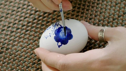 Woman applying floral pattern on eggshell of chicken egg painted white paint. 4K Stock Footage 124260605
