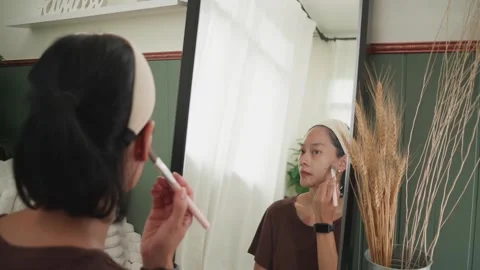 Woman Applying Foundation While Looking at Herself in the Mirror Stock Footage 310356305