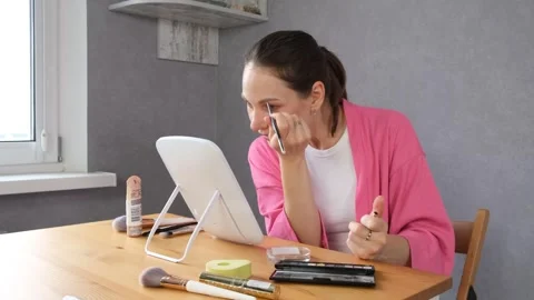 A woman applying makeup at a mirror vanity table Stock Footage 318748669