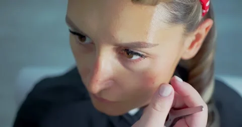 Woman Applying Makeup with Precision Tool in Salon 스톡 동영상 323493505