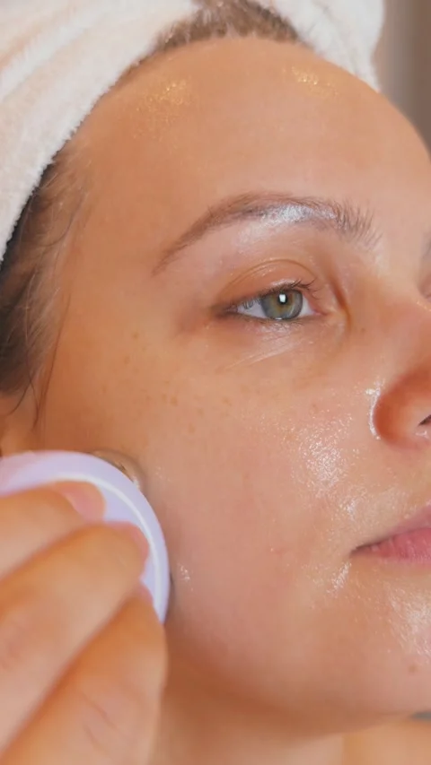 Woman applying microcurrent device to her face, promoting anti aging and Stock Footage 340521828