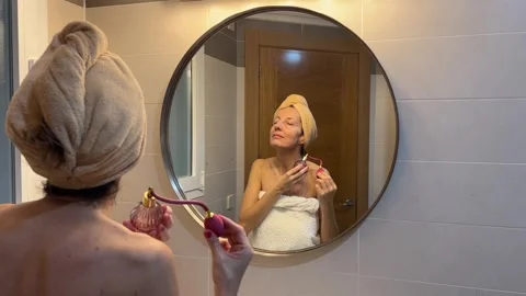 Woman applying perfume in front of mirror during beauty routine Stock-Footage 329074059