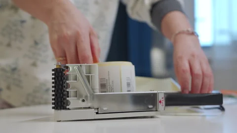 Woman applying shipping barcode labels with handheld label applicator to packets Stock Footage 261668084