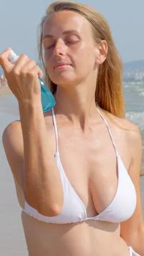 Woman Applying SPF Sunscreen Spray on Face at Sunny Beach Stock Photos