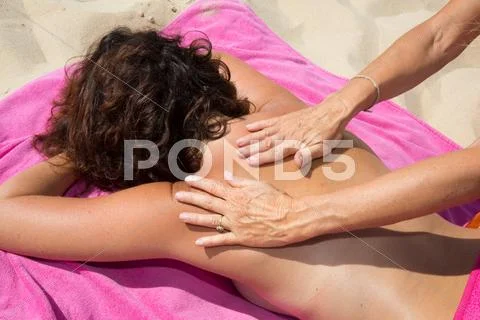 Woman applying sun cream on woman's back while in holidays Stock Photos