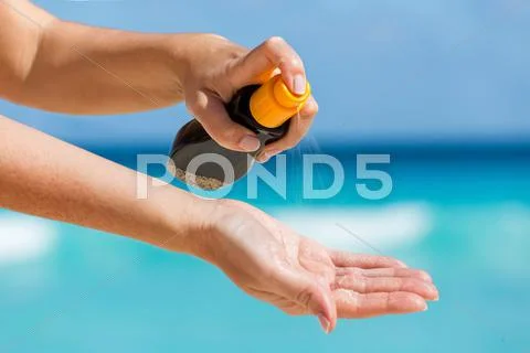 Woman applying sunscreen protection cream against turquoise caribbean sea wat Stock Photos