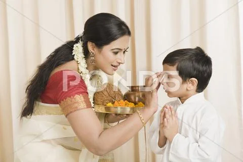 Woman applying tilak to her son Stock Photos