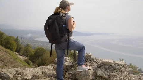 Woman approaches edge of cliff and admires breathtaking view of sea Stock Footage