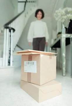 Woman approaching stack of delivery boxes on foyer floor 写真素材