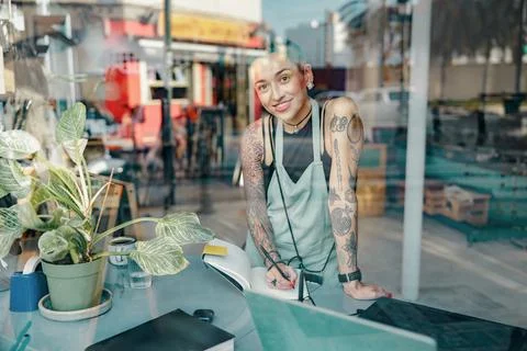 Woman in apron making notes in notebook during working day in design studio and 스톡 사진