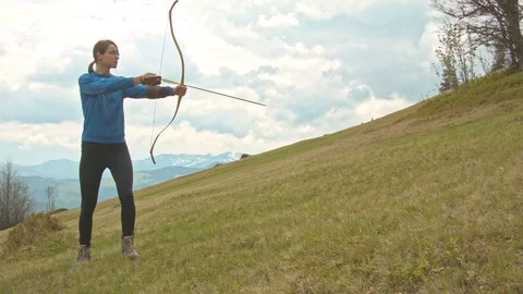 Woman archer shoots with a bow in the mountains in spring Video stock 80490953