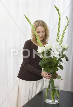A woman arranging a bouquet of sword lilies and roses Stock Photos