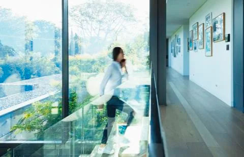 Woman ascending stairs in sunny modern, luxury home Stock Photos