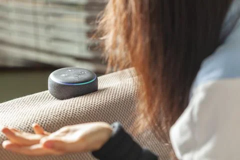 Woman asking question to amazon echo dot device Stock Photos