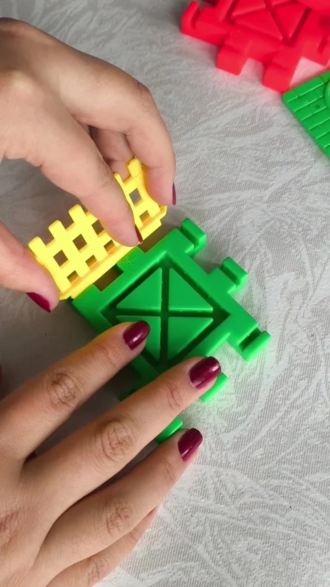 A woman assembles a close-up of a construction set on a table. Games for Stock Footage 318205493
