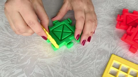 A woman assembles a close-up of a construction set on a table. Games for Stock Footage 318205579