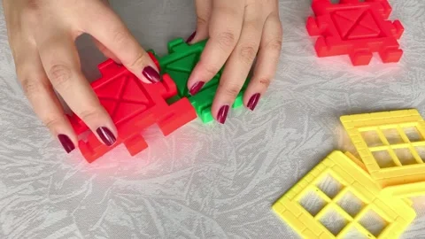 A woman assembles a close-up of a construction set on a table. Games for Stock Footage 318205652