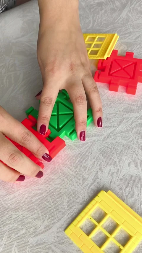 A woman assembles a close-up of a construction set on a table. Games for Stock Footage 318205688