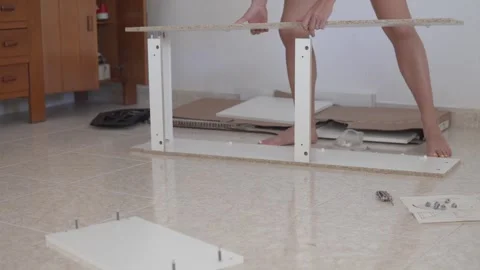 A woman assembles a shoe rack according to the instructions at home Stock Footage 253191412