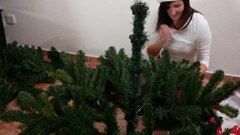 Woman assembling an artificial Christmas tree on floor Stock Footage 163365371